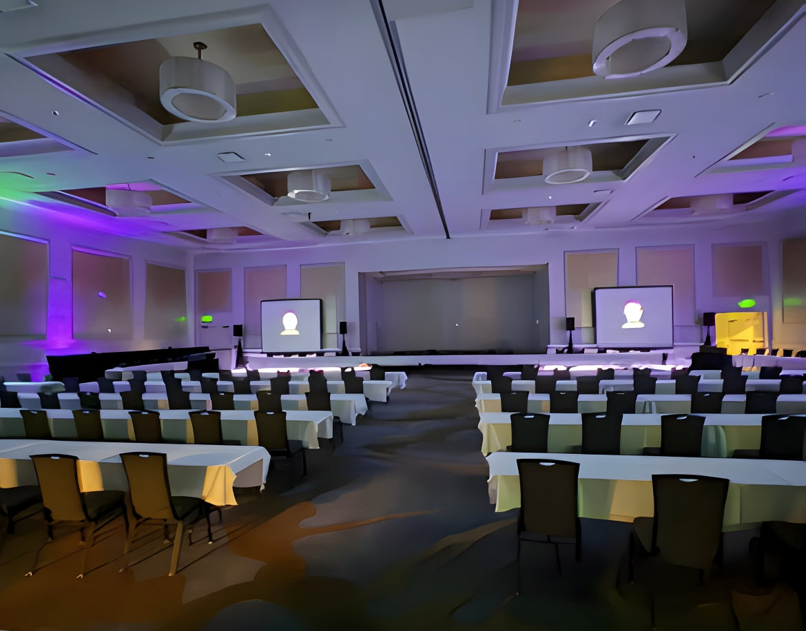 Professional speaker stage setup featuring dual projection screens and clear audio-visual integration for a corporate presentation.