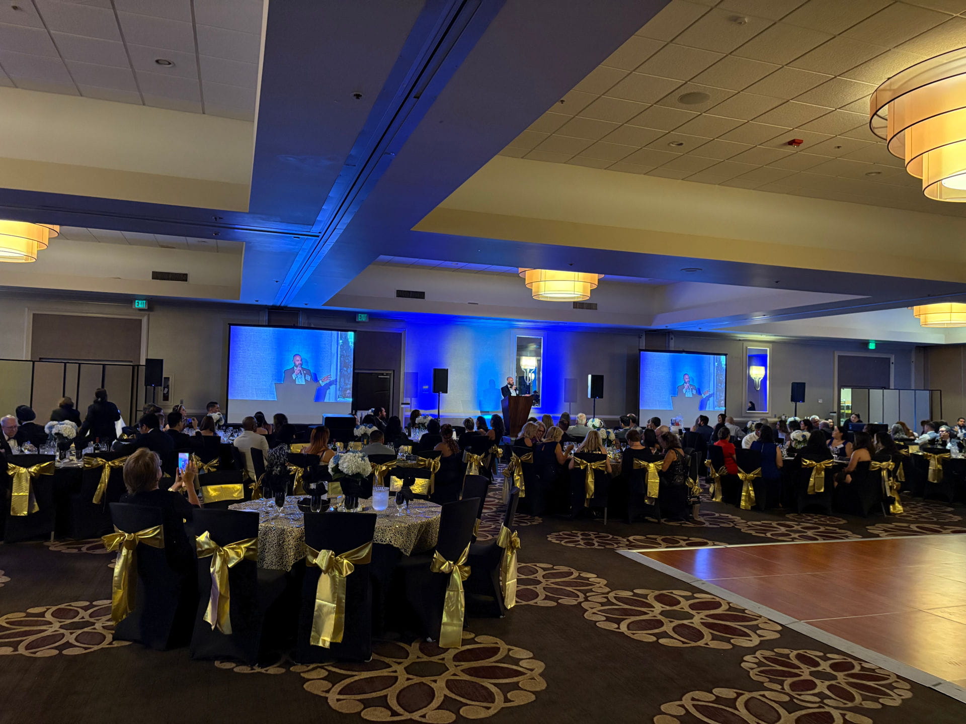 Warm ambient uplighting and stage production setup for a San Francisco Bay Area charity gala and evening celebration.
